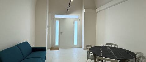 Una habitación amplia con sofá, una mesa de comedor con sillas y un sistema de iluminación en el techo.