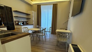 A modern kitchen with a central island, a dining area with a table and chairs, and a living area with a TV. - B&B PALAZZO CROGHAN (Torremaggiore)