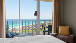 Habitación de hotel con un amplio ventanal corredero que da a un balcón con vistas al océano y a la zona del resort.