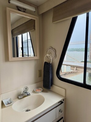 Een badkamer met een wastafel, spiegel, handdoekrek en een raam met uitzicht op een brug en water.