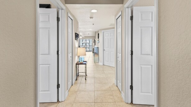 A hallway with white doors, a lamp on a small table, and a ceiling fan.