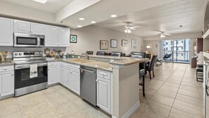A modern kitchen with white cabinets, stainless steel appliances, and a large island.