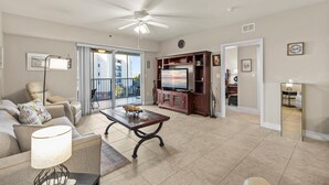 A spacious living room with a ceiling fan, a TV, and a dining area with a table and chairs.