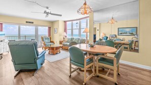 Un vaste espace de vie comprenant une table à manger, des chaises, un canapé et un ventilateur de plafond.