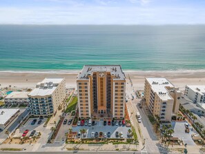 A high-rise hotel with a beach view, parking, and a pool area.