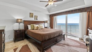 Un dormitorio amplio con una cama grande, un ventilador de techo y un balcón con vistas al océano.
