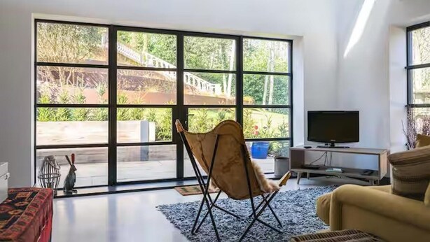 A modern living room with large windows, a flat-screen TV, and a comfortable seating area. - Aylesford-house-sleeps 2 & 1 Infant-parking-garden (Aylesford)