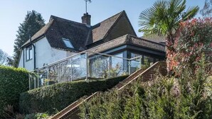 A modern house with a glass conservatory, a patio with a table and chairs, and a brick wall. - Aylesford-house-sleeps 2 & 1 Infant-parking-garden (Aylesford)
