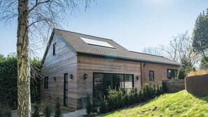 A modern two-story house with a sloped roof, large windows, and a visible garage. - Aylesford-house-sleeps 2 & 1 Infant-parking-garden (Aylesford)