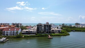 Un hotel frente al mar con varias edificaciones, un muelle con un bote y una vista despejada del océano.