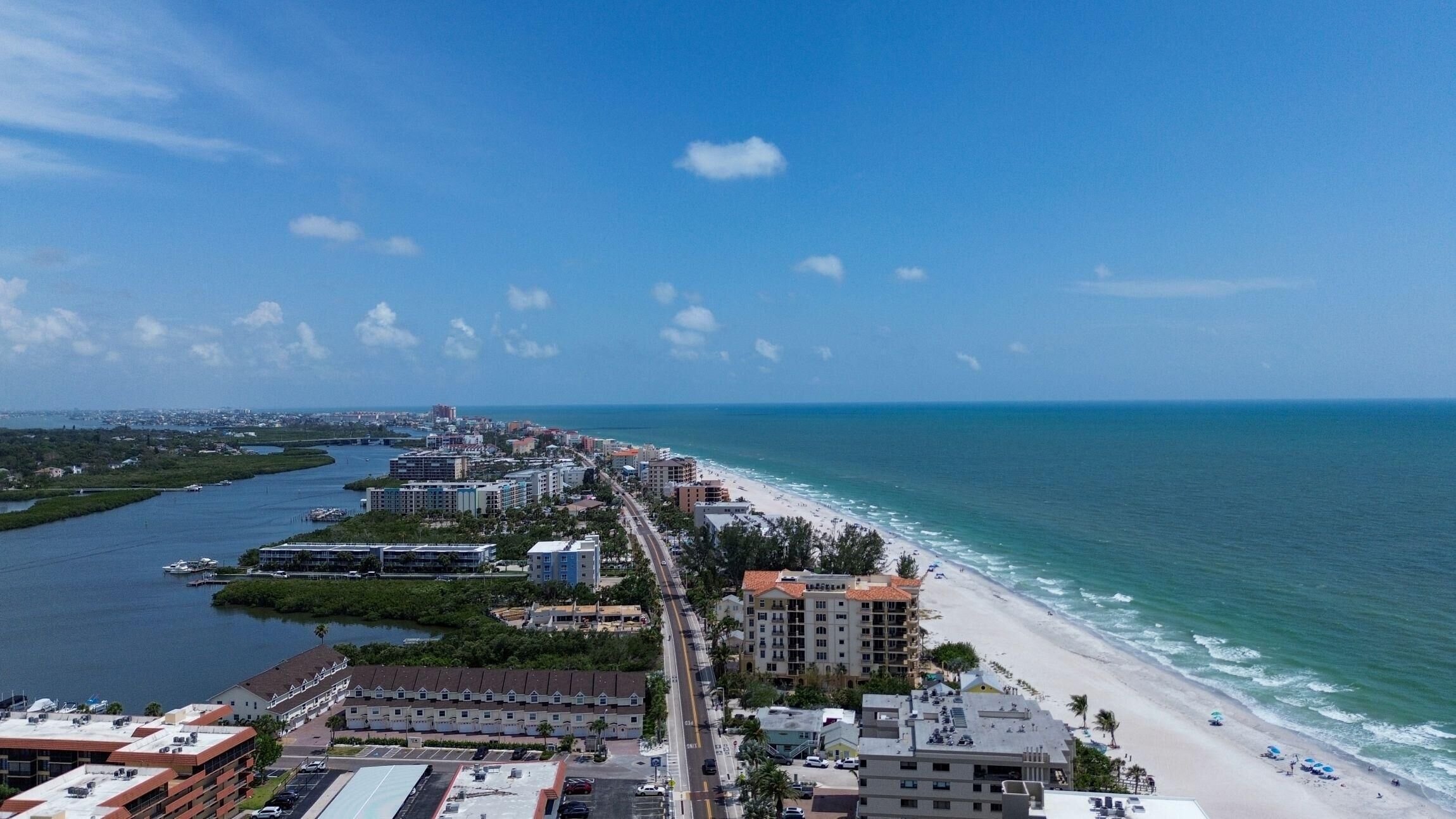 A coastal cityscape with a beach, buildings, and a marina.