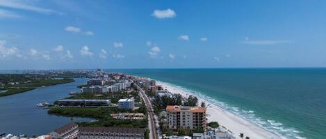 A coastal cityscape with a beach, buildings, and a marina.