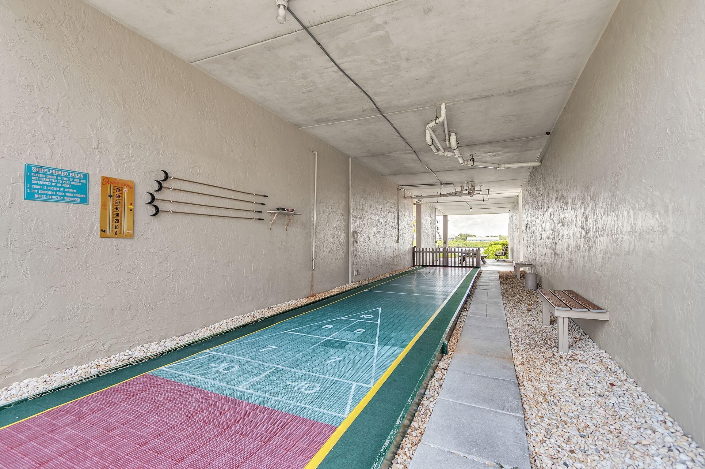 A hallway with a shuffleboard court, a bench, and a sign indicating the court's rules.