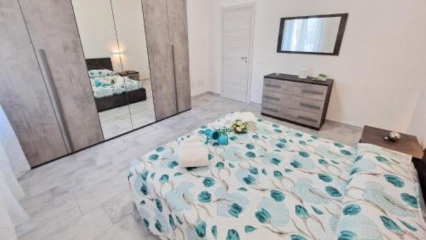 A bedroom with a bed, a dresser, a mirror, and a wardrobe.