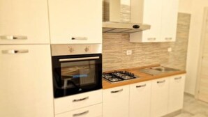 A modern kitchen with white cabinetry, a built-in oven, and a gas stove.
