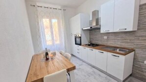 A compact kitchen with white cabinets, a wooden countertop, and a built-in oven.
