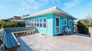 A turquoise building with a deck, a bench, and a small table. - 703 By The Sea by Topsail Realty (Holly Ridge)