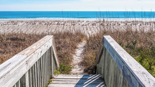 A wooden boardwalk leading to a beach with a clear view of the ocean. - 703 By The Sea by Topsail Realty (Holly Ridge)