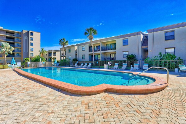 Relax by the pool surrounded by comfortable lounge chairs and umbrellas.