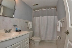 Bathroom features a sink, mirror, toilet, shower curtain, and towel.