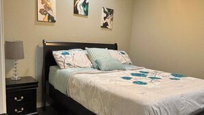 Une chambre à coucher comprenant un lit, une table de chevet, une lampe et trois œuvres d’art murales.