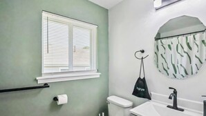 Een badkamer met toilet, wastafel en raam met zonwering.