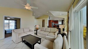 A living room with two sofas, a coffee table, a ceiling fan, and a view of the kitchen. - Barefoot Bungalow by Topsail Realty (Holly Ridge)