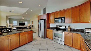A modern kitchen with wooden cabinets, stainless steel appliances, and a granite countertop. - Barefoot Bungalow by Topsail Realty (Holly Ridge)