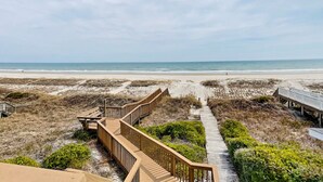 A beach view with a wooden boardwalk leading to the shore. - Barefoot Bungalow by Topsail Realty (Holly Ridge)
