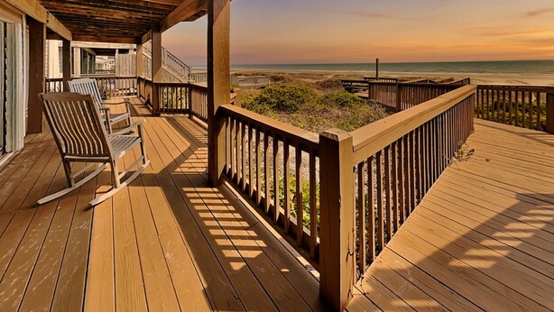 A wooden deck with a railing, chairs, and a view of the beach. - Barefoot Bungalow by Topsail Realty (Holly Ridge)