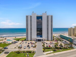 Un hotel moderno con un atrio central, aparcamiento y vistas a la playa.