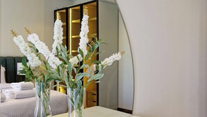 A modern bathroom with a large mirror, white vanity, and two clear vases with white flowers.