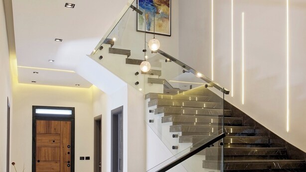 A modern interior with a staircase, a sofa, and a wooden door.