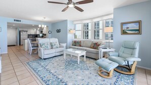 A spacious living room with a ceiling fan, a light blue sofa, a white coffee table, and a patterned rug. - Ponce de Leon Towers 301 (New Smyrna Beach)