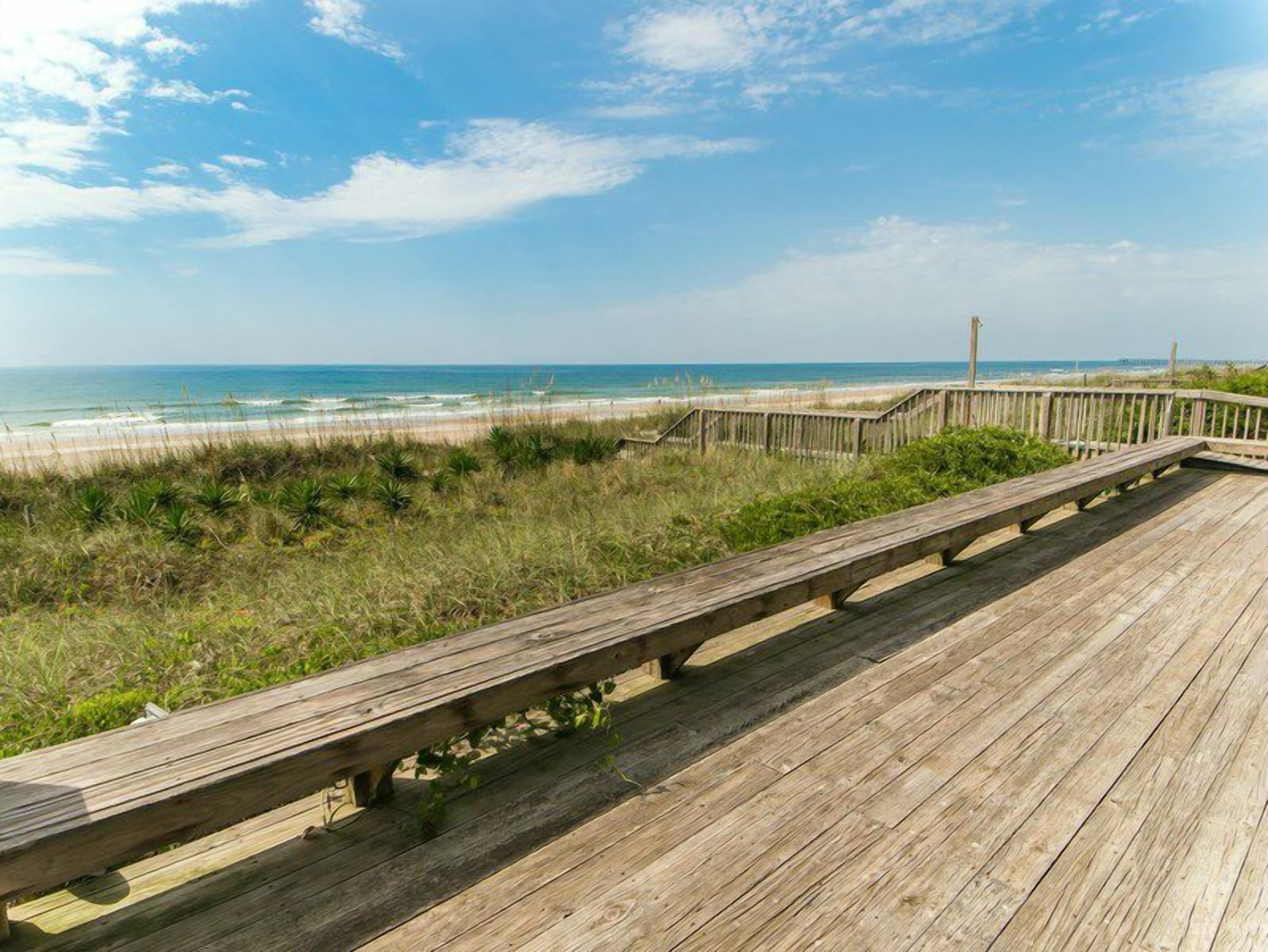 A wooden boardwalk leading to a beach with a clear sky.