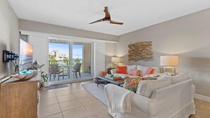 A modern living room with a ceiling fan, a sofa, a coffee table, and a TV on a wooden cabinet.