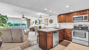 A modern kitchen with wooden cabinets, stainless steel appliances, and a large island. - Sea Club #104 - Casa con Vista (Indian Shores)