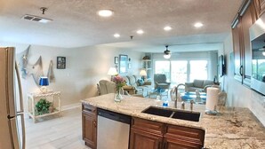 A spacious kitchen with granite countertops, a dishwasher, and a large island with a sink. - Sea Club #104 - Casa con Vista (Indian Shores)