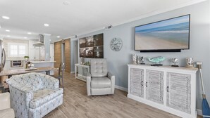 Una sala de estar moderna con un sofá, un sillón y un televisor de pantalla plana grande.