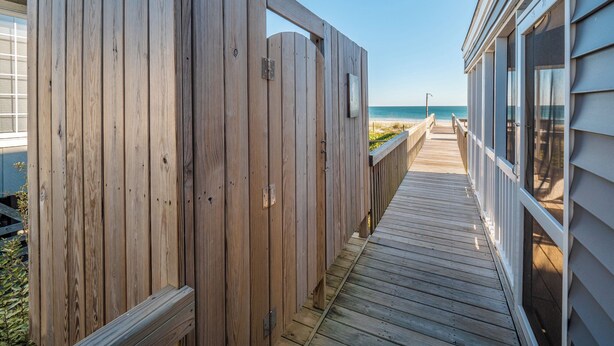A wooden deck leading to a beach with a clear view of the ocean. - Blue Crab by Topsail Realty (Holly Ridge)