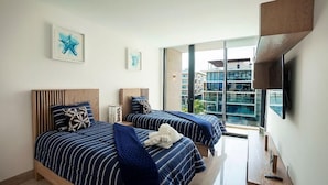 A hotel room with two beds, a TV, and a large window with a city view. - Ocd35- Luxury Condo With Ocean View (Playa del Carmen)