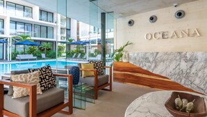A modern hotel lobby with a pool, lounge chairs, and a reception desk. - Ocd35- Luxury Condo With Ocean View (Playa del Carmen)