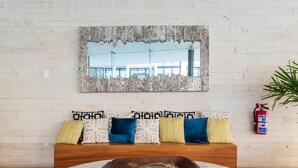 A modern living room with a wooden bench, patterned cushions, a marble coffee table, and a large mirror on the wall. - Ocd35- Luxury Condo With Ocean View (Playa del Carmen)