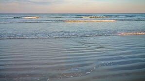 A beach with waves gently lapping at the shore. - Colony Beach Club 248 (New Smyrna Beach)
