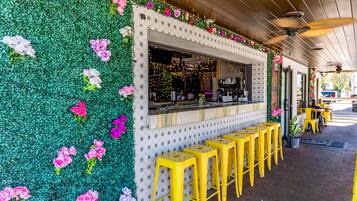 En restaurant med en grøn væg dekoreret med blomster, en disk med barstole og en loftsvifte.