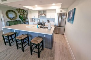Una cucina moderna con isola centrale, sgabelli da bar, elettrodomestici in acciaio inossidabile e uno specchio decorativo.