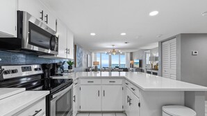 Una cocina moderna con armarios blancos, una estufa de acero inoxidable y una isla grande.