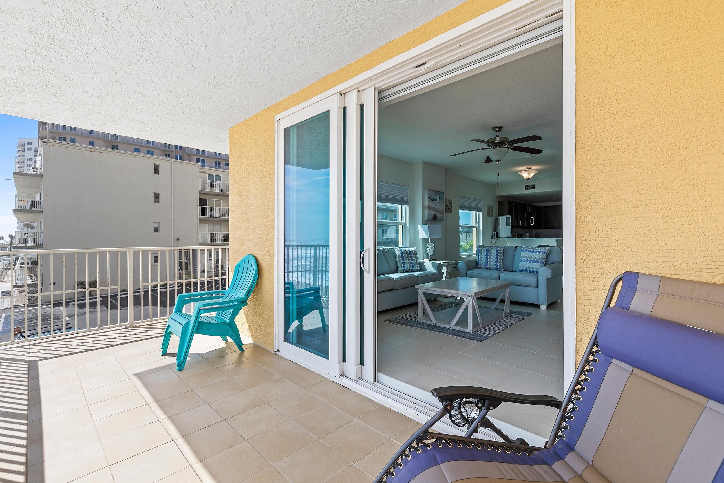 A balcony with a sliding glass door leading to a living area with a sofa, coffee table, and a ceiling fan.