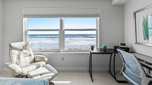 A room with a view of the ocean, a reclining chair, a desk with a globe, and a framed picture on the wall. - Aruba 206 (Daytona Beach Shores)