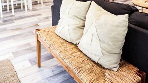 Una sala de estar moderna con sofá, banco tejido y comedor con mesa y sillas.